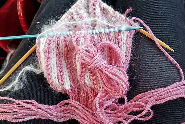 Checking the remaining length to knit out the pink.