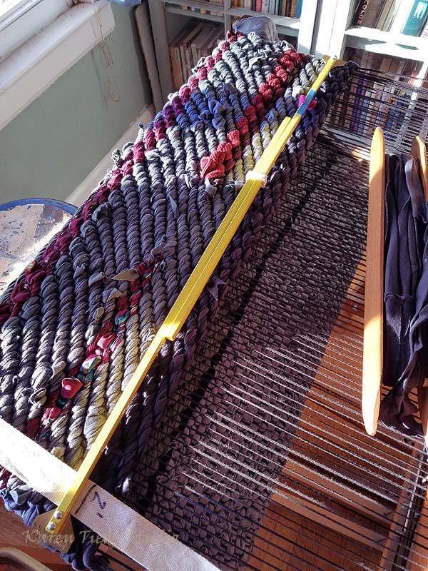 Third line. (The line at the left of the picture is the 9 in second place.) Gray weaving shown through the warp is spacer fiber; the rug itself starts with the black line.